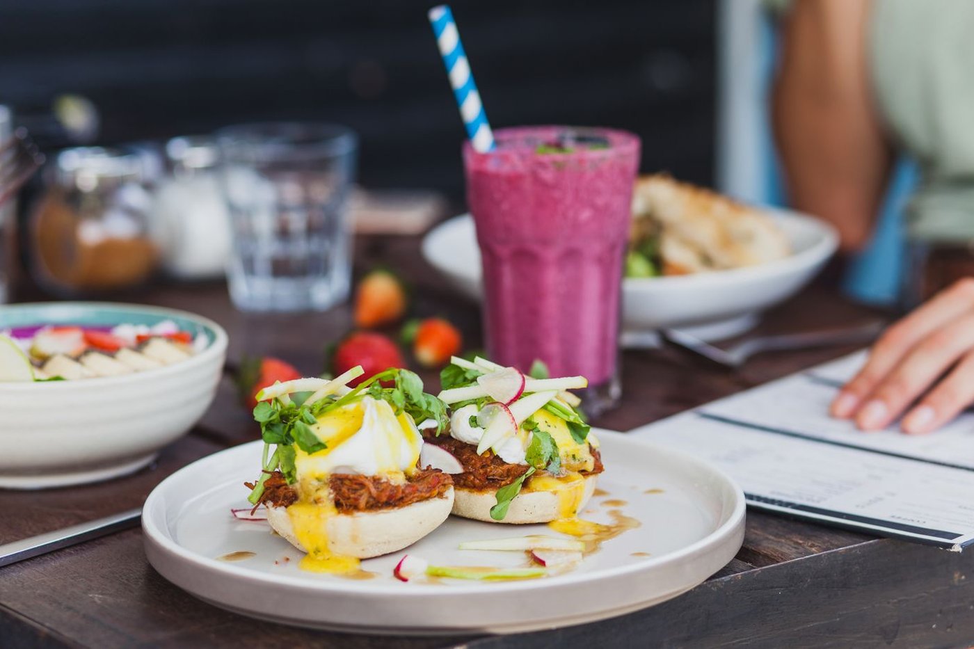 An overhead view of a brunch spread with eggs, fresh fruit, and coffee on a café table