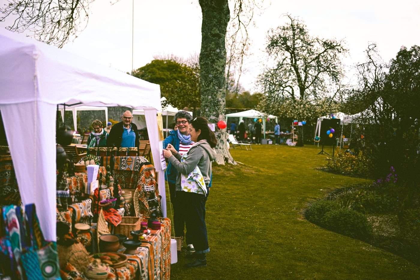 A crowded outdoor arts and crafts market with vendor tents and visitors browsing booths in a park setting, used here as a representative image